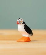Bumbu Toys puffin handmade wooden toy figure placed on a wooden surface. 