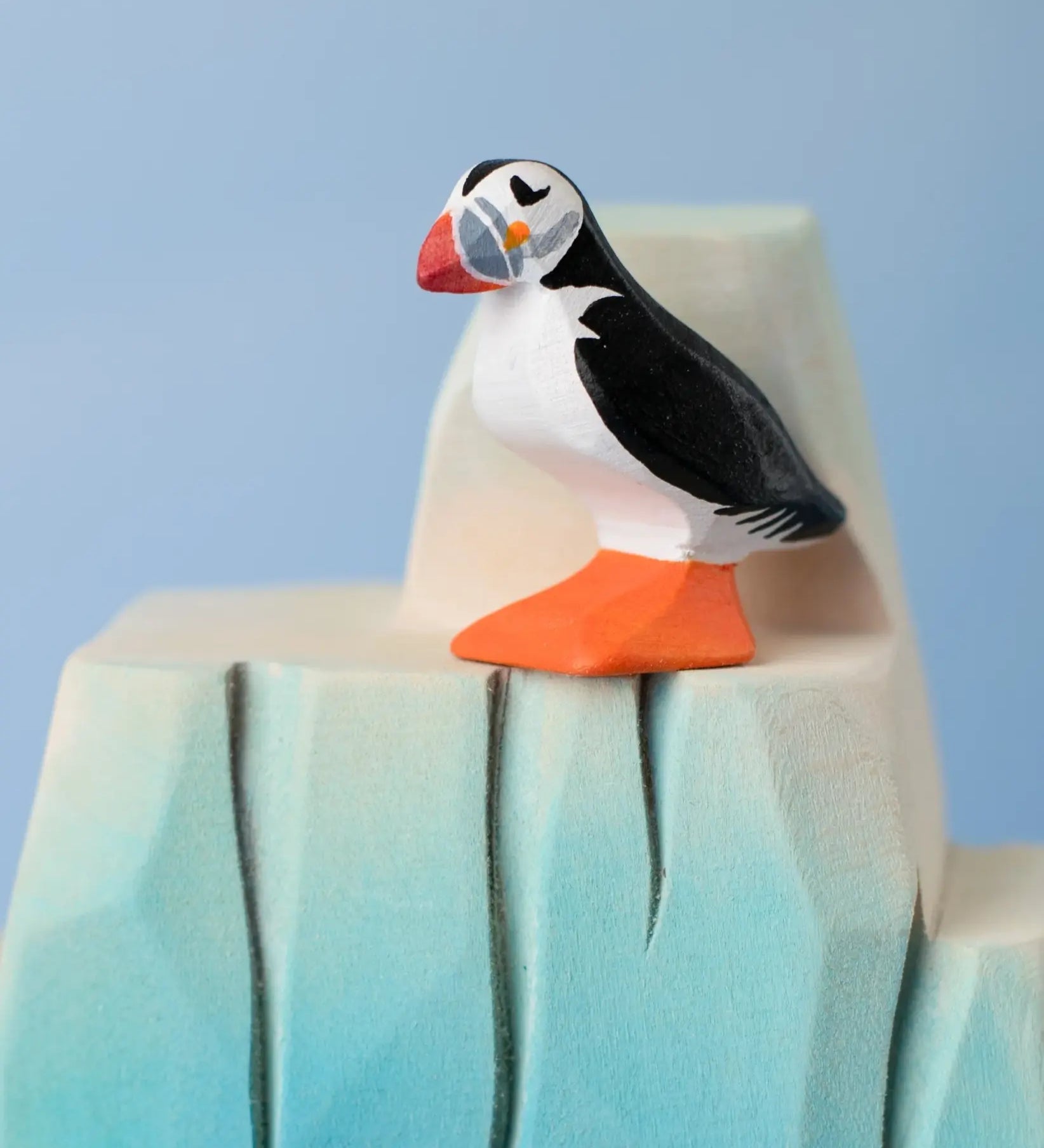 Bumbu Toys puffin handmade wooden toy figure placed on a wooden ice berg scenery piece.