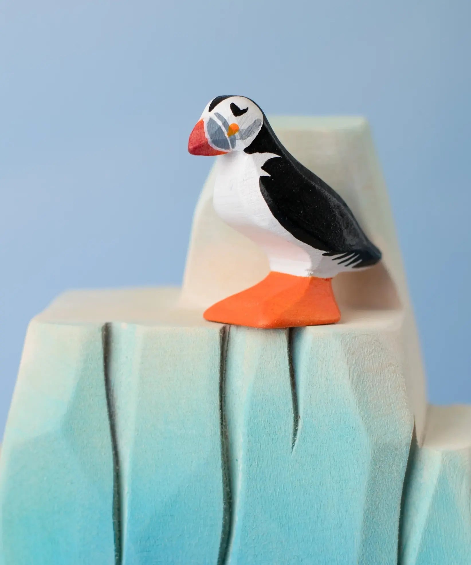 Bumbu Toys puffin handmade wooden toy figure placed on a wooden ice berg scenery piece.