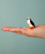 Bumbu Toys puffin handmade wooden toy figure on an adult's hand.