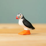Bumbu Toys puffin handmade wooden toy figure placed on a wooden surface. 