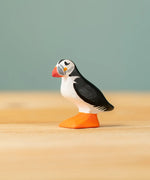 Bumbu Toys puffin handmade wooden toy figure placed on a wooden surface. 