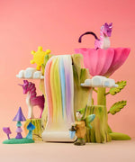 A Bumbu Toys Rainbow Cliff set up in a small world play scene featuring Bumbu Unicorns, mushrooms and flowers. 