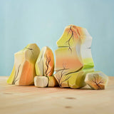 The Bumbu Toys Rainbow Rocks are wooden figures hand painted with green, orange background and brown and white coloured detailing. 