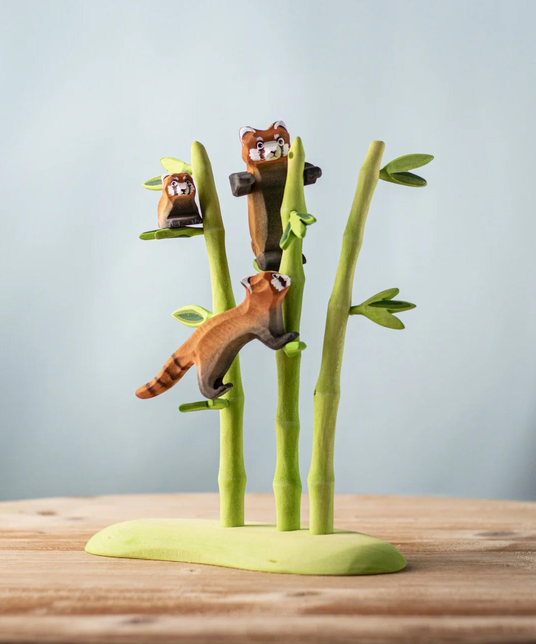 A nature play scene featuring the playful, cub and standing red panda balancing on the Bumbu bamboo. 
