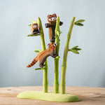 A nature play scene featuring the playful, cub and standing red panda balancing on the Bumbu bamboo. 