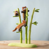 A nature play scene featuring the playful, cub and standing red panda balancing on the Bumbu bamboo. 