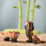 A family of the Bumbu wooden red pandas on a wooden board with the Bumbu bamboo in the background