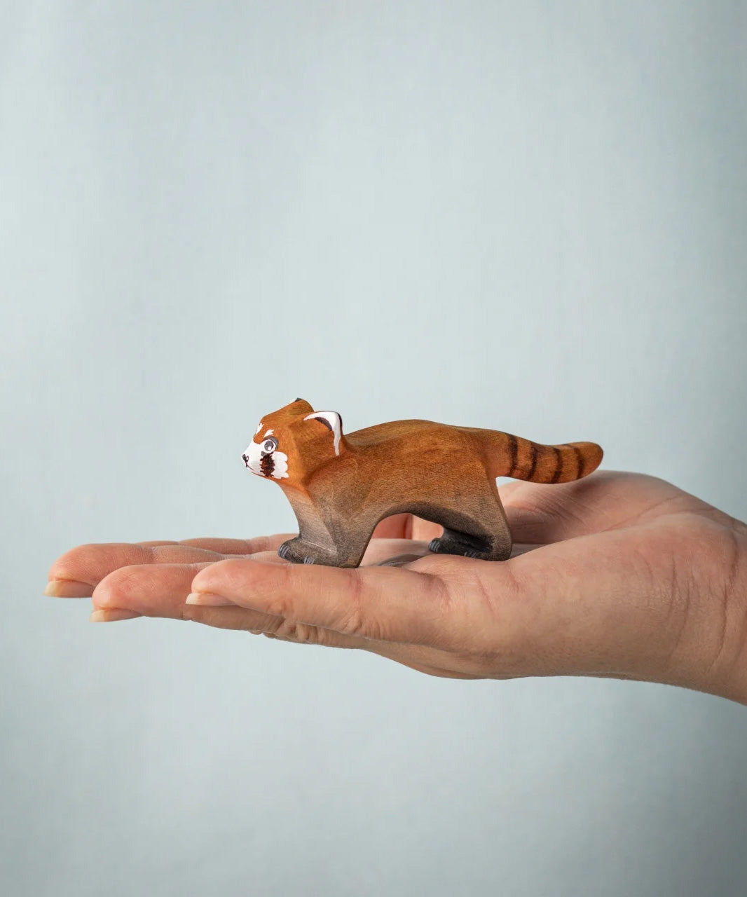 A hand holding the Bumbu red panda figure