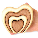 Hand holding the wooden Bumbu stacking heart in front of a white background