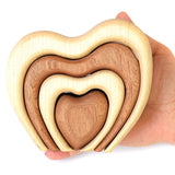 Hand holding the wooden Bumbu stacking heart in front of a white background