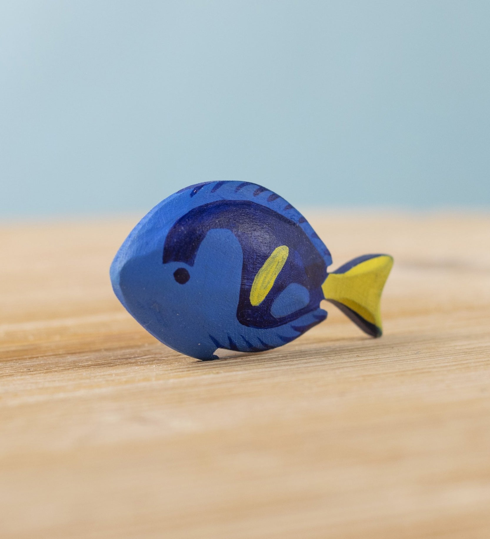 The Bumbu hand carved wooden Royal Blue Tang fish toy, hand painted in blue with yellow details. 