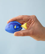 The Bumbu Royal Blue Tang fish wooden toy, held by a hand for size reference
