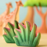 Bumbu Toys savanna bush wooden toy scenery figure placed in a small world play scene with giraffes in the background.