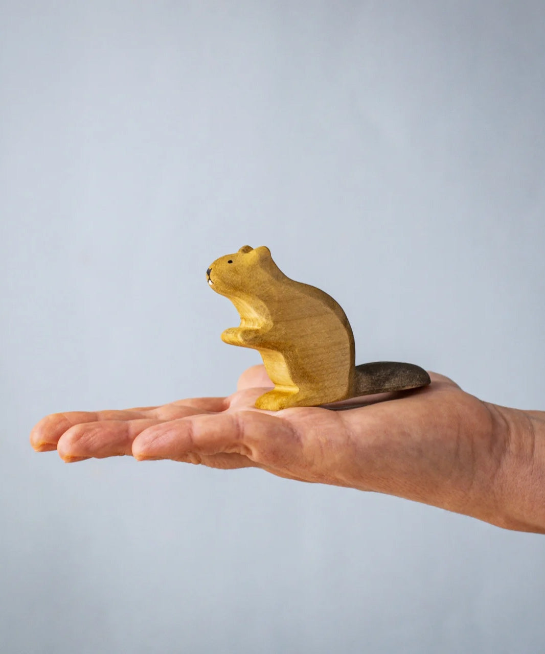 A hand holding the Bumbu wooden sitting beaver figure