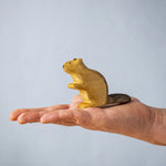 A hand holding the Bumbu wooden sitting beaver figure