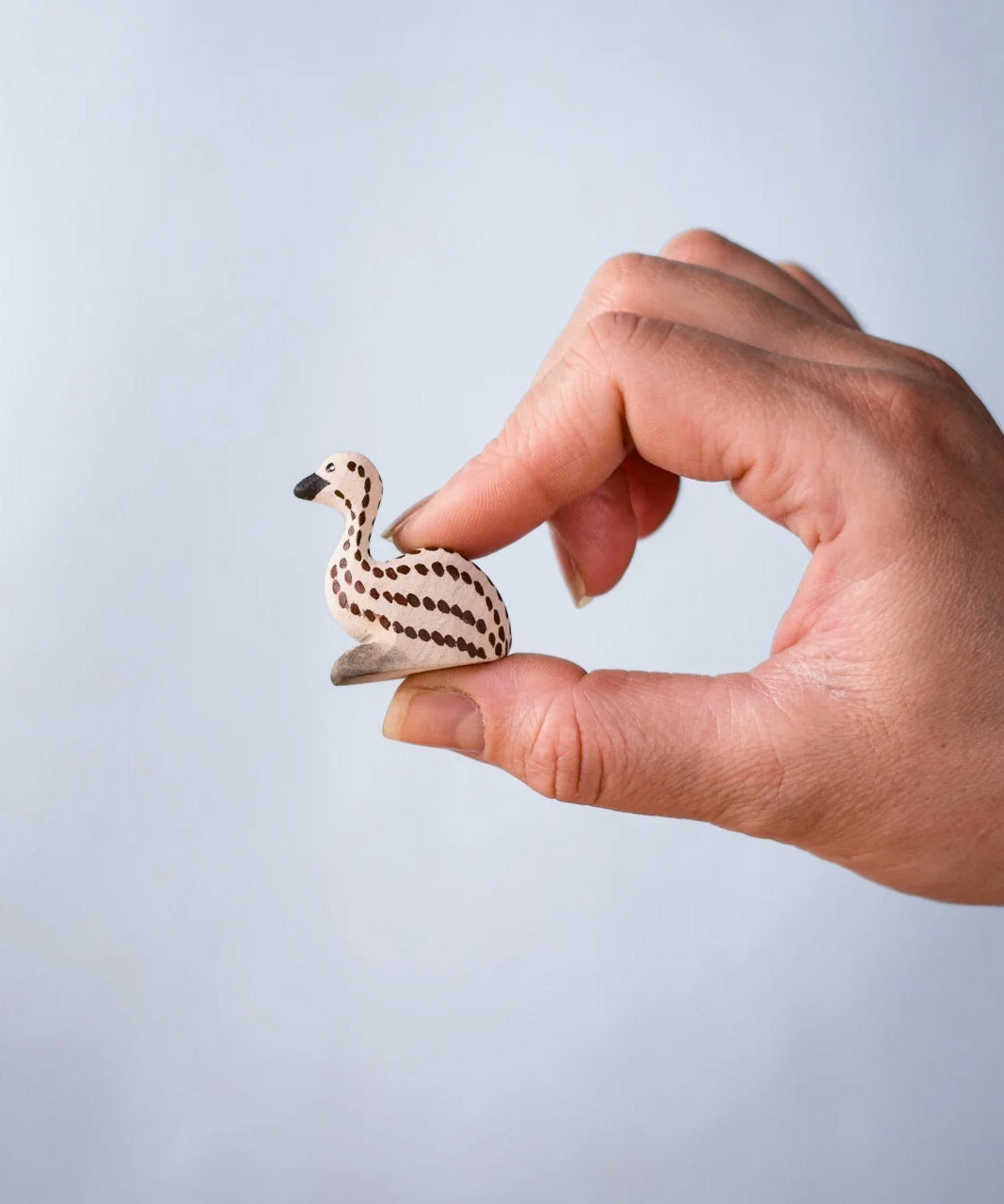 A hand holding the Bumbu wooden emu chick