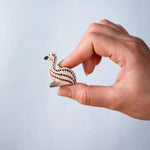 A hand holding the Bumbu wooden emu chick
