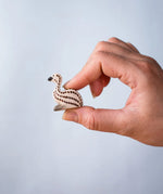 A hand holding the Bumbu wooden emu chick