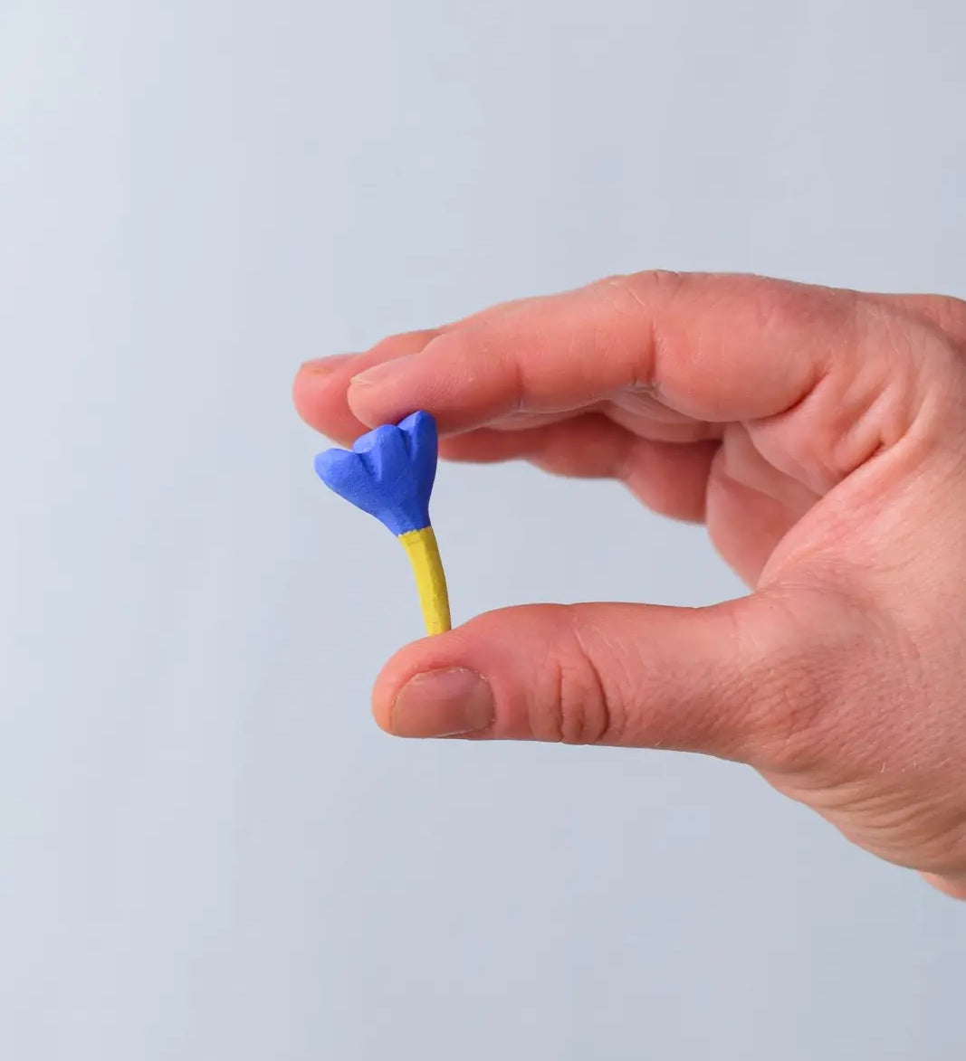 Bumbu blue small wooden flower wooden toy scenery in an adult's hand.