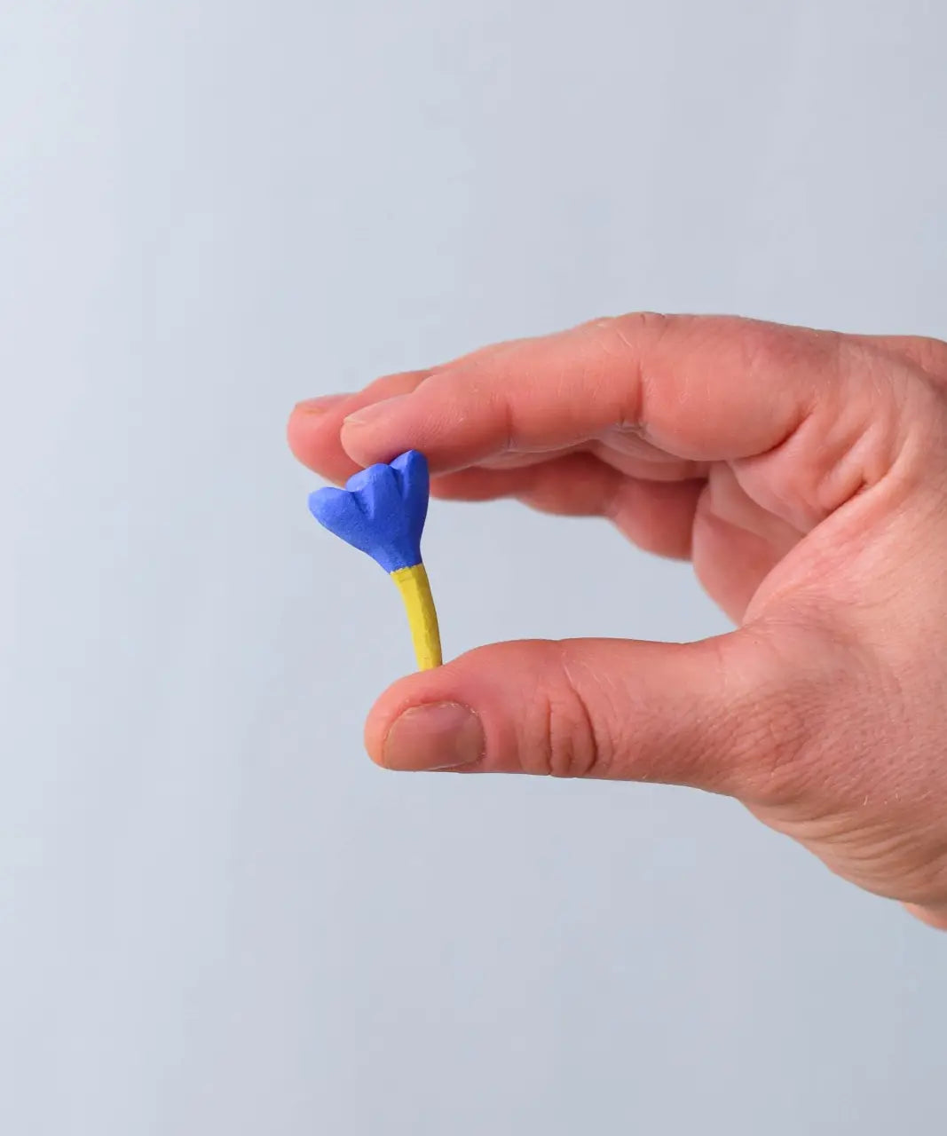 Bumbu blue small wooden flower wooden toy scenery in an adult's hand.