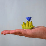 Bumbu small wooden grass with blue flower for use as scenery in an adult's hand.