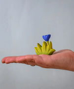 Bumbu small wooden grass with blue flower for use as scenery in an adult's hand.