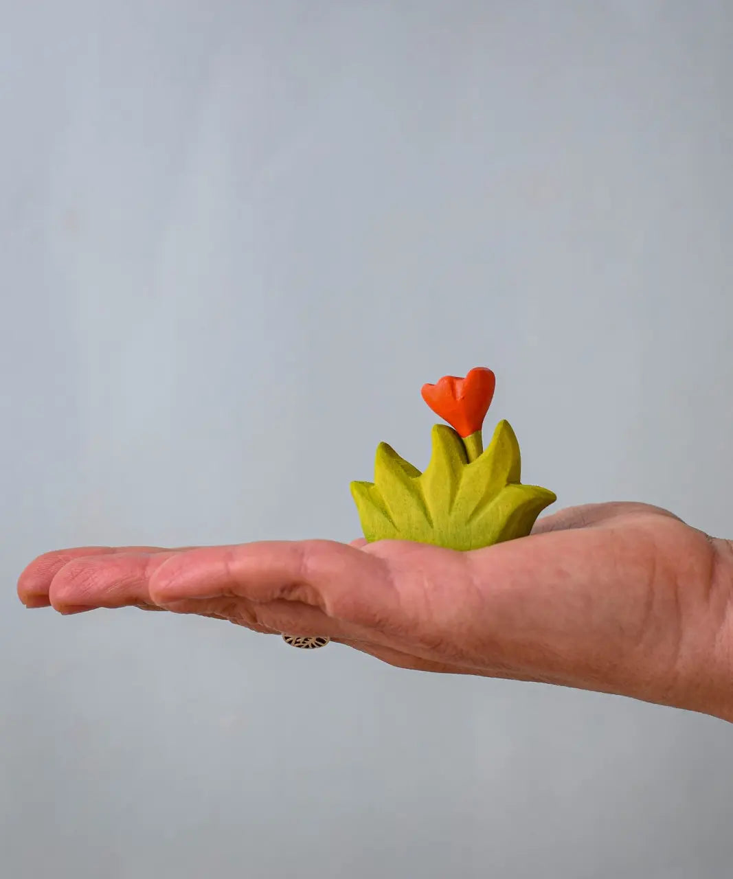 Bumbu small wooden grass with orange flower scenery piece in an adult's hand.