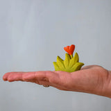 Bumbu small wooden grass with orange flower scenery piece in an adult's hand.