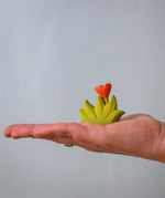 Bumbu small wooden grass with orange flower scenery piece in an adult's hand.