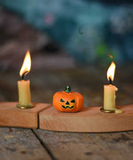 A small Bumbu Halloween figure placed on a wooden Grimm's celebration ring in between to lit candles.