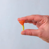 Bumbu Toys small wooden flower in orange in an adult's hand.