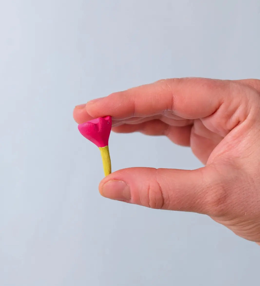 Bumbu Toys small wooden flower in pink in an adult's hand. 
