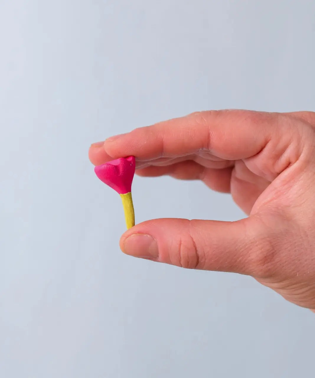 Bumbu Toys small wooden flower in pink in an adult's hand. 