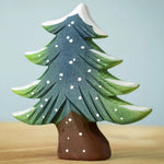 A Bumbu Small Snowy Fir Tree placed on a wooden surface.