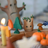 A small Bumbu spooky tree figure placed on a natural Grimm's celebration ring decorated with Halloween themed figures. 