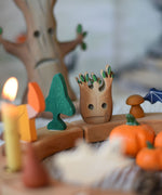 A small Bumbu spooky tree figure placed on a natural Grimm's celebration ring decorated with Halloween themed figures. 