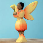 A Bumbu Small Wooden Flower in Yellow shown placed in the sunflower fairy's hands