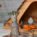 A large and small Bumbu spooky tree figures placed next to each other in front of an Ostheimer cottage. 
