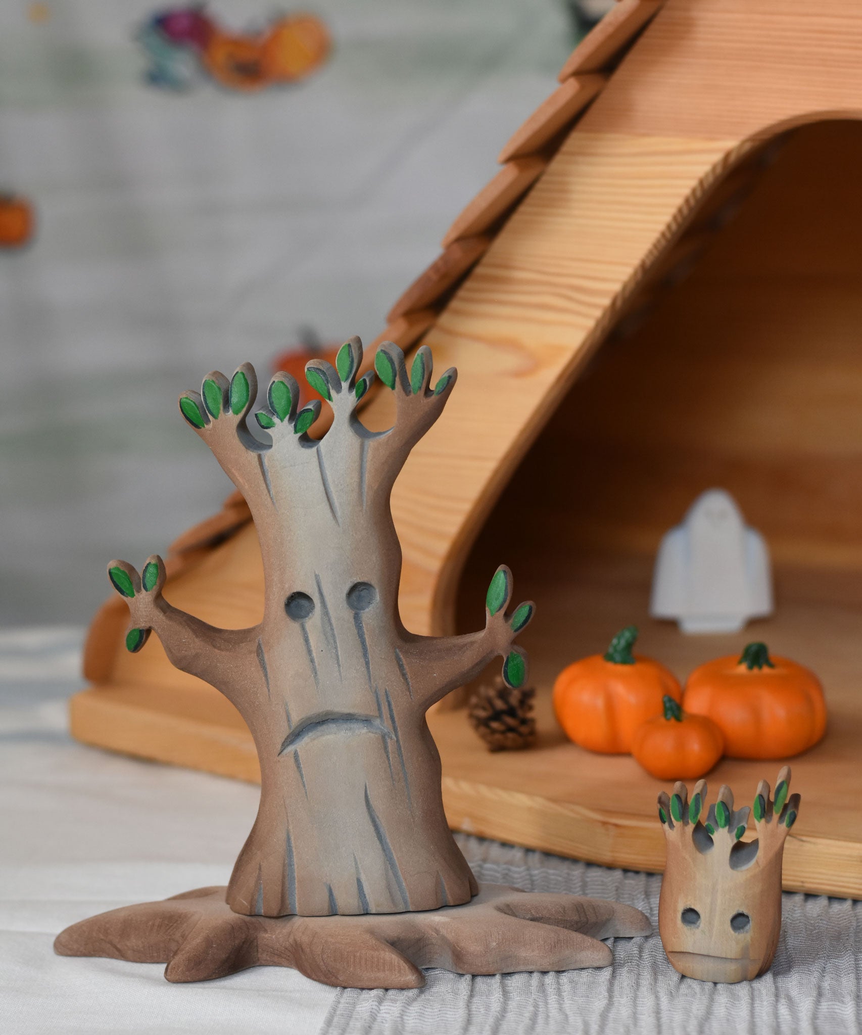 A large and small Bumbu spooky tree figures placed next to each other in front of an Ostheimer cottage. 