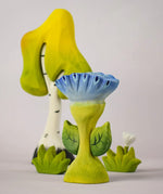 The Bumbu Toys Flama Spring Flower shown in front of a Bumbu birch tree an white flower. 