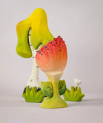 The front of a Bumbu Toys Perla Spring Flower shown in front of a Bumbu tree and white flower. 