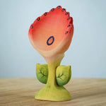 The Bumbu Toys Perla Spring Flower has a red flower with blue detailing and a green coloured stem. 
