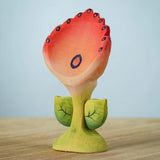 The Bumbu Toys Perla Spring Flower has a red flower with blue detailing and a green coloured stem. 