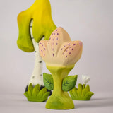 The Bumbu Toys Zia Spring Flower shown in front of a Bumbu tree and white flower. 
