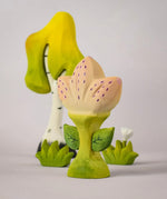 The Bumbu Toys Zia Spring Flower shown in front of a Bumbu tree and white flower. 