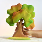 Hand holding the eco-friendly Bumbu autumn oak tree on a wooden background