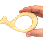 Hand holding the Bumbu sustainable wooden whale baby teething toy on a white background