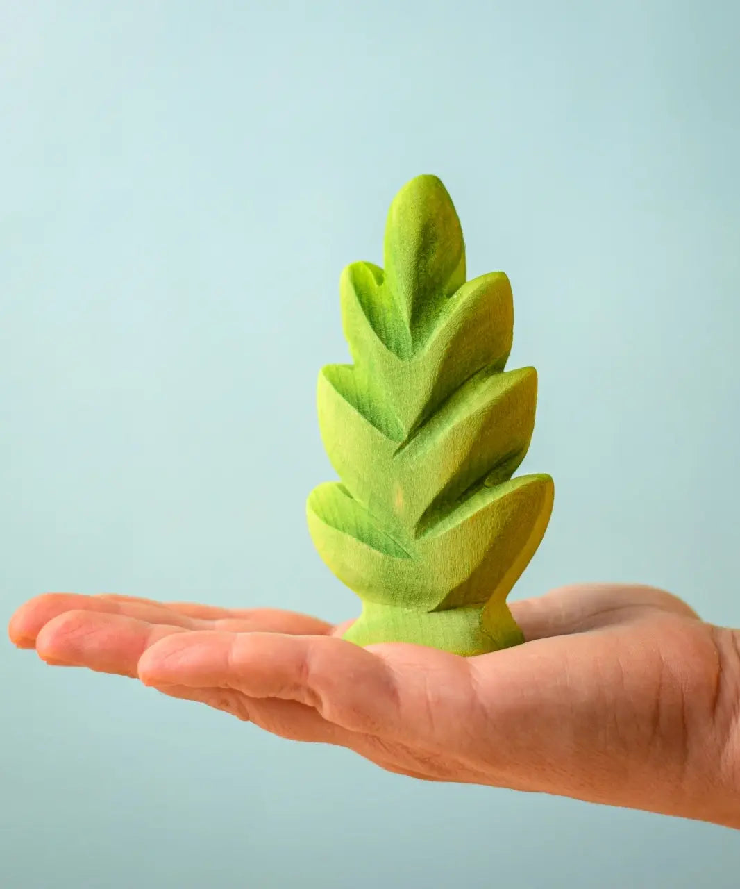 Bumbu Toys thuja shrub wooden toy scenery piece placed on an adult's hand.