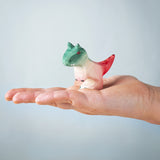 A Bumbu Toys handmade wooden Baby Carnotaurus dinosaur figure shown on an adult's hand. 
